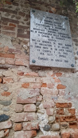 Lapidi commemorative in un contesto di rastrellamento, con un muro di mattoni in evidenza.