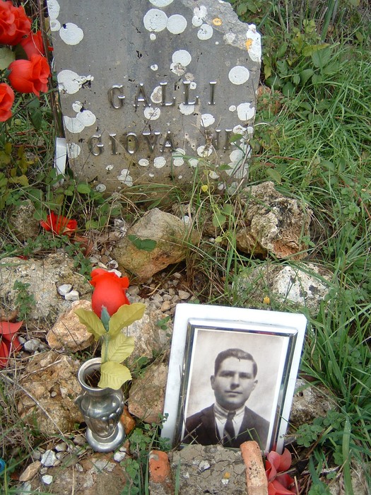 Cippi commemorativi in memoria dei caduti di Montemaggio, con fiori e una fotografia.