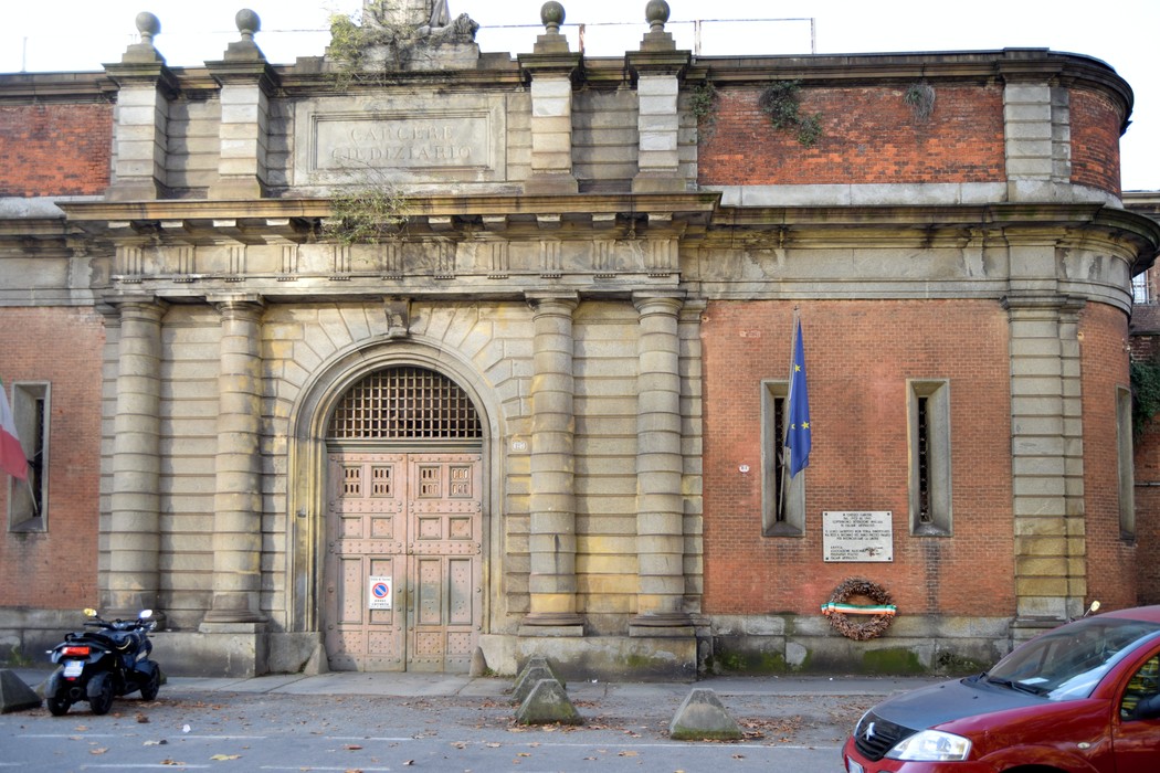 Lapide commemorativa in onore dei detenuti antifascisti, situata presso le Carceri Nuove, con un edificio storico sullo sfondo.