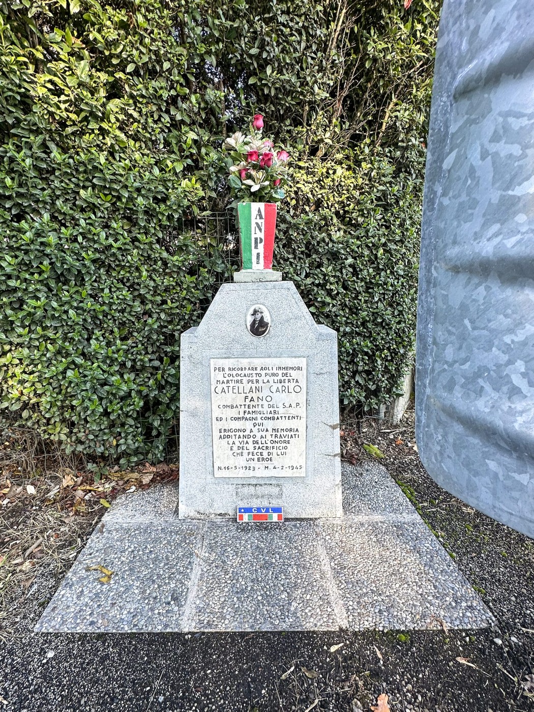 Cippo commemorativo dedicato a Carlo Catellani, con fiori e simboli della resistenza.