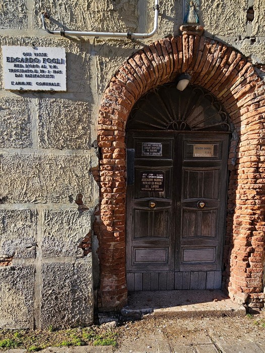 Lapide dedicata a Edoardo Fogli, situata su una storica porta in muratura.