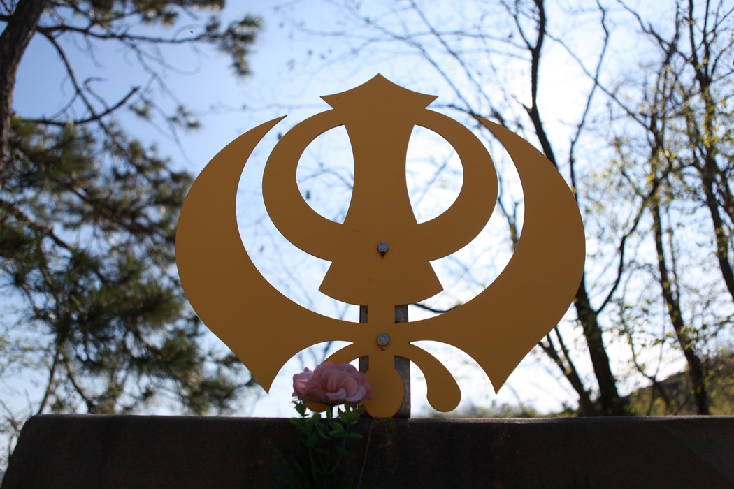 Monumento per la Battaglia della Cavallara, con simbolo stilizzato e un fiore in primo piano.