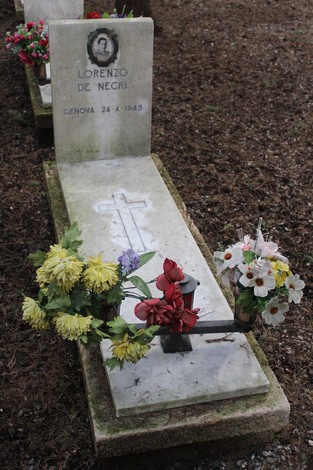 Tomba decorata con fiori in memoria di Lorenzo De Negri, con croce e fotografia commemorativa.