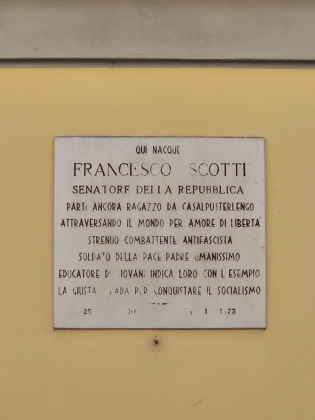 Lapide commemorativa dedicata a Francesco Scotti, senatore della Repubblica, situata su una parete.