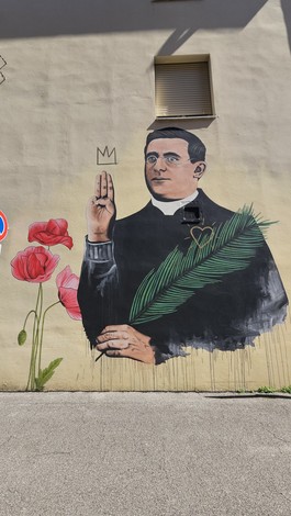 Murale che rappresenta un uomo in abito ecclesiastico con palme e fiori in primo piano.