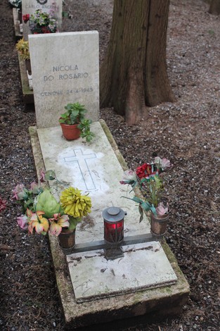 Tombe con fiori e candele, commemorano i caduti per la Libertà in un ambiente sereno.