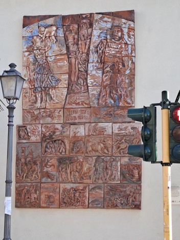 Bassorilievo che celebra la Liberazione, con figure simboliche e scene di resistenza e speranza.