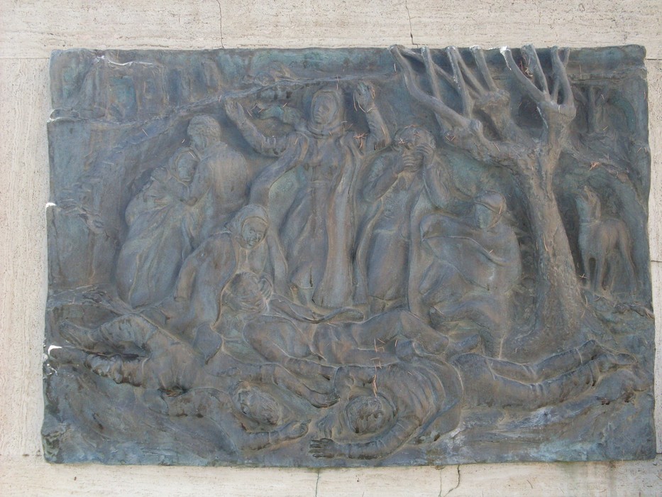 Bassorilievo commemorativo dedicato ai caduti della Guerra di Liberazione, evocante sofferenza e resistenza.