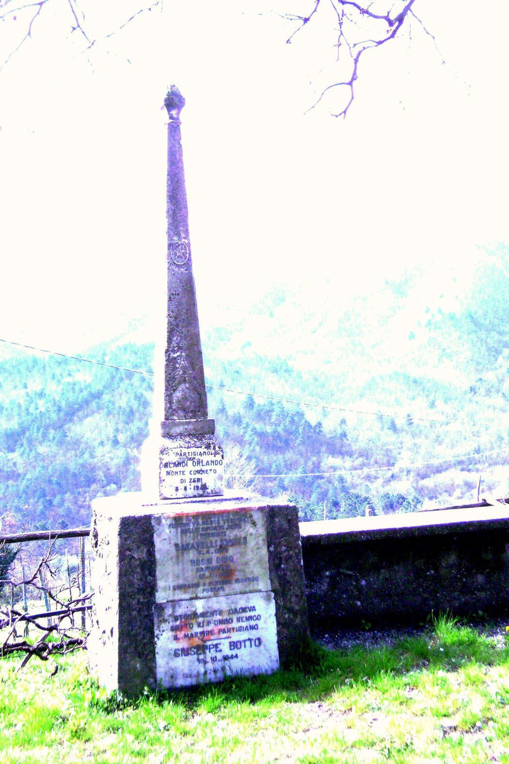 Cippo commemorativo in memoria di Garavelli, Rossi e altri, situato in un paesaggio montano.