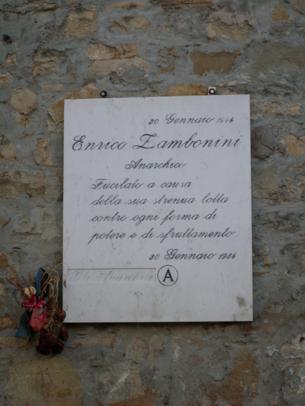 Lapide commemorativa di Enrica Zambonini, anarchica, posta su una parete di pietra.