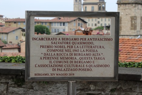 Targa commemorativa dedicata a Salvatore Quasimodo a Bergamo, con riferimento alla sua poesia e al premio Nobel.