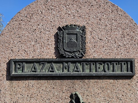 Monumento a Matteotti con un'iscrizione su base di pietra e un emblema araldico.