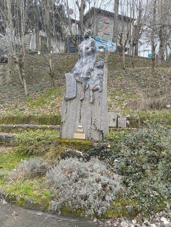 Monumento ai caduti di Quinzano, raffigurante una figura femminile con un bambino su uno sfondo naturale.