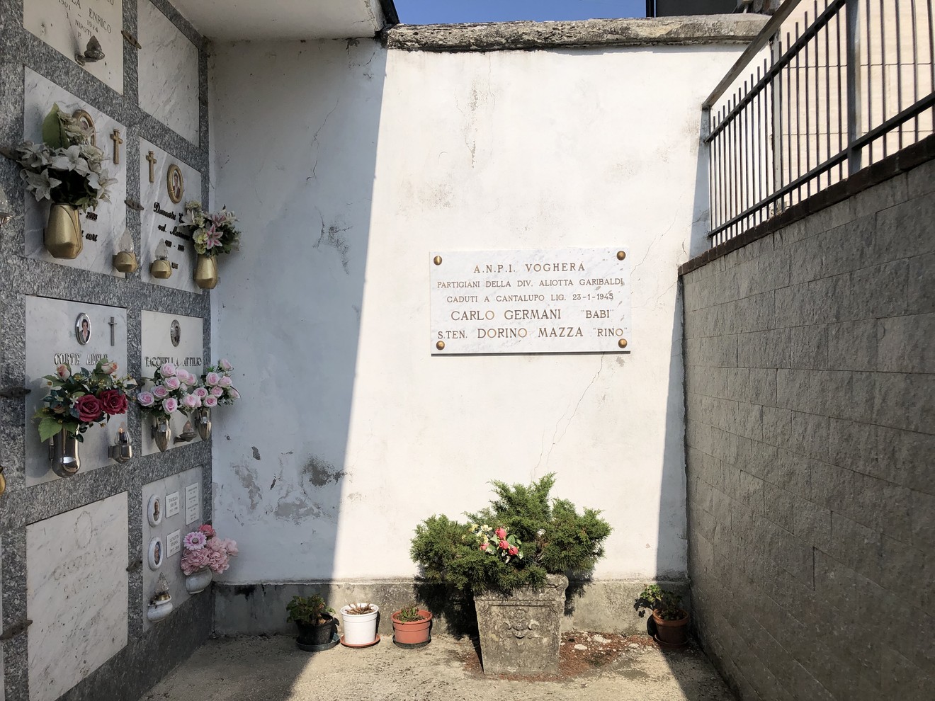 Lapide commemorativa dedicata a Carlo Germani e Bino Mazza, con fiori e tributi nel cimitero.