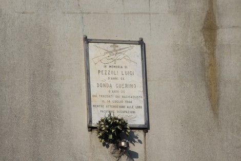 Lapide commemorativa dedicata a Donda Guerino e Pezzoli Luigi, con simboli e decorazioni floreali.