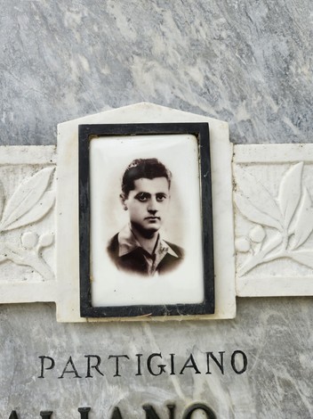 Lapide commemorativa di un partigiano, con una foto incassata su marmo decorato.