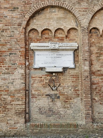 Lapide commemorativa su una parete in mattoni, dedicata a Pietrobuoni, Barbieri e Bettini.