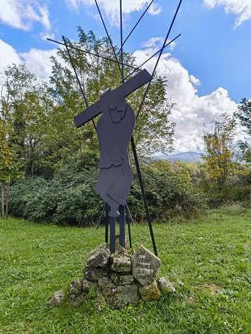 Scultura della Via Crucis di Casaglia, che rappresenta il cammino di Cristo verso la crocifissione in un paesaggio naturale.