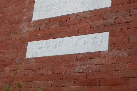 Lapide commemorativa su un muro di mattoni, simbolo di memoria e riconciliazione storica.
