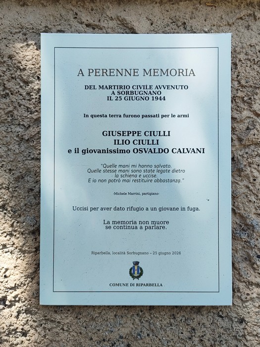 Targa commemorativa in marmo su parete intonacata, con iscrizione e stemma comunale nella parte inferiore.