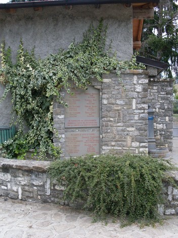 Lapide commemorativa in onore dei caduti del Distaccamento Amendola, decorata da vegetazione.
