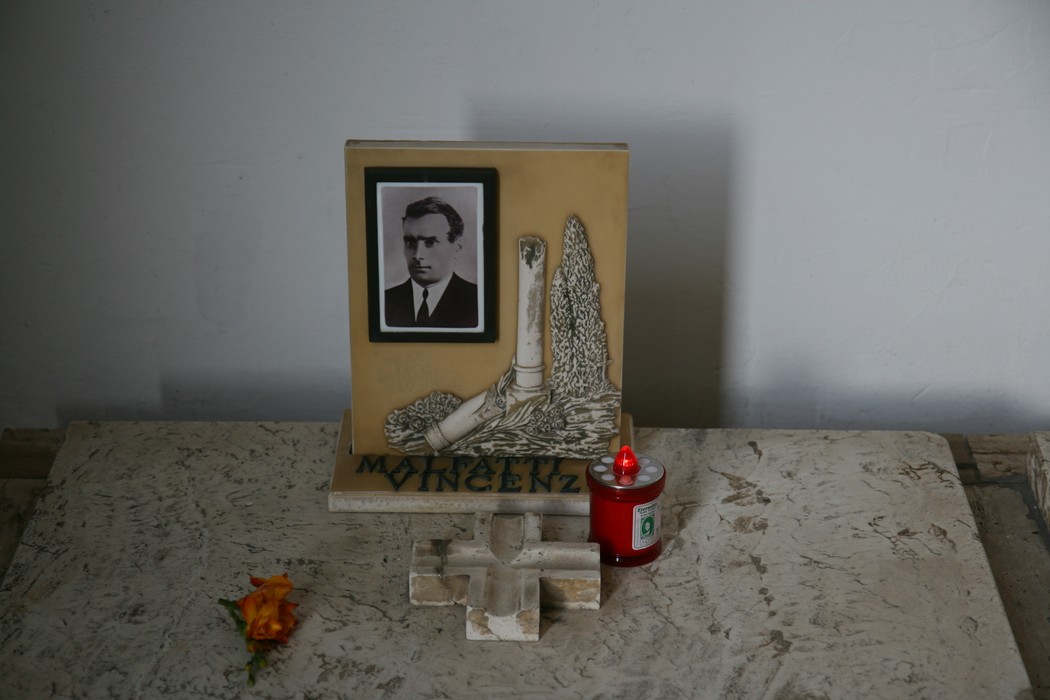 Monumento ai martiri di San Terenzo con una foto e candele, simbolo di memoria e rispetto.