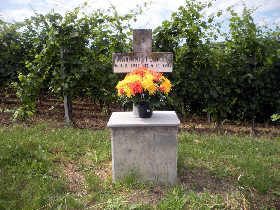 Croce a Battaini con fiori in un vigneto, memoria di una persona defunta.