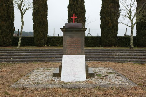 Monumento commemorativo nell'area di Sant'Andrea, circondato da alberi e scalini, con una croce rossa.