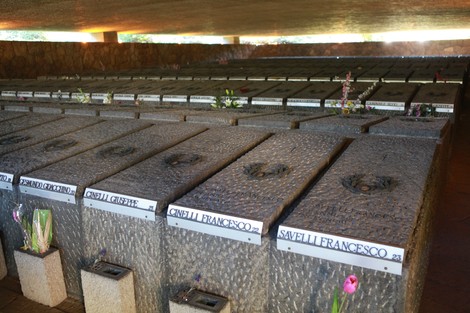Interno del Mausoleo delle Fosse Ardeatine con tombe in muratura e fiori freschi. Luogo di commemorazione.