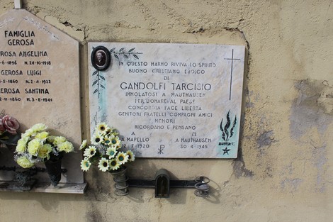 Lapide commemorativa di Gandolfi Tarcisio, decorata con fiori, situata in un cimitero.
