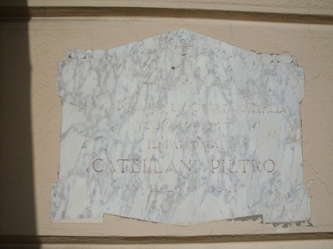 Lapide commemorativa dedicata a Catellani Piltro, in marmo, su fondo chiaro.