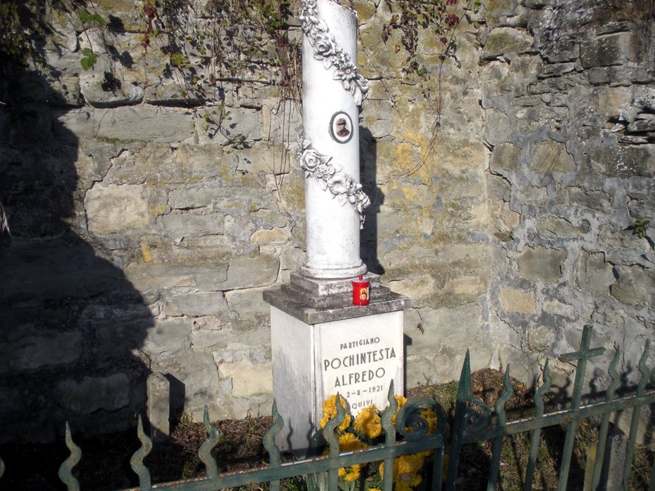 Cippo commemorativo a Pochintesta, dedicato a Alfredo, immerso nella natura e circondato da una recinzione.