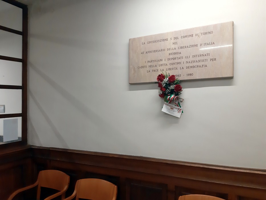 Lapide commemorativa della Circoscrizione V per il 45° anniversario della Liberazione, decorata con fiori.