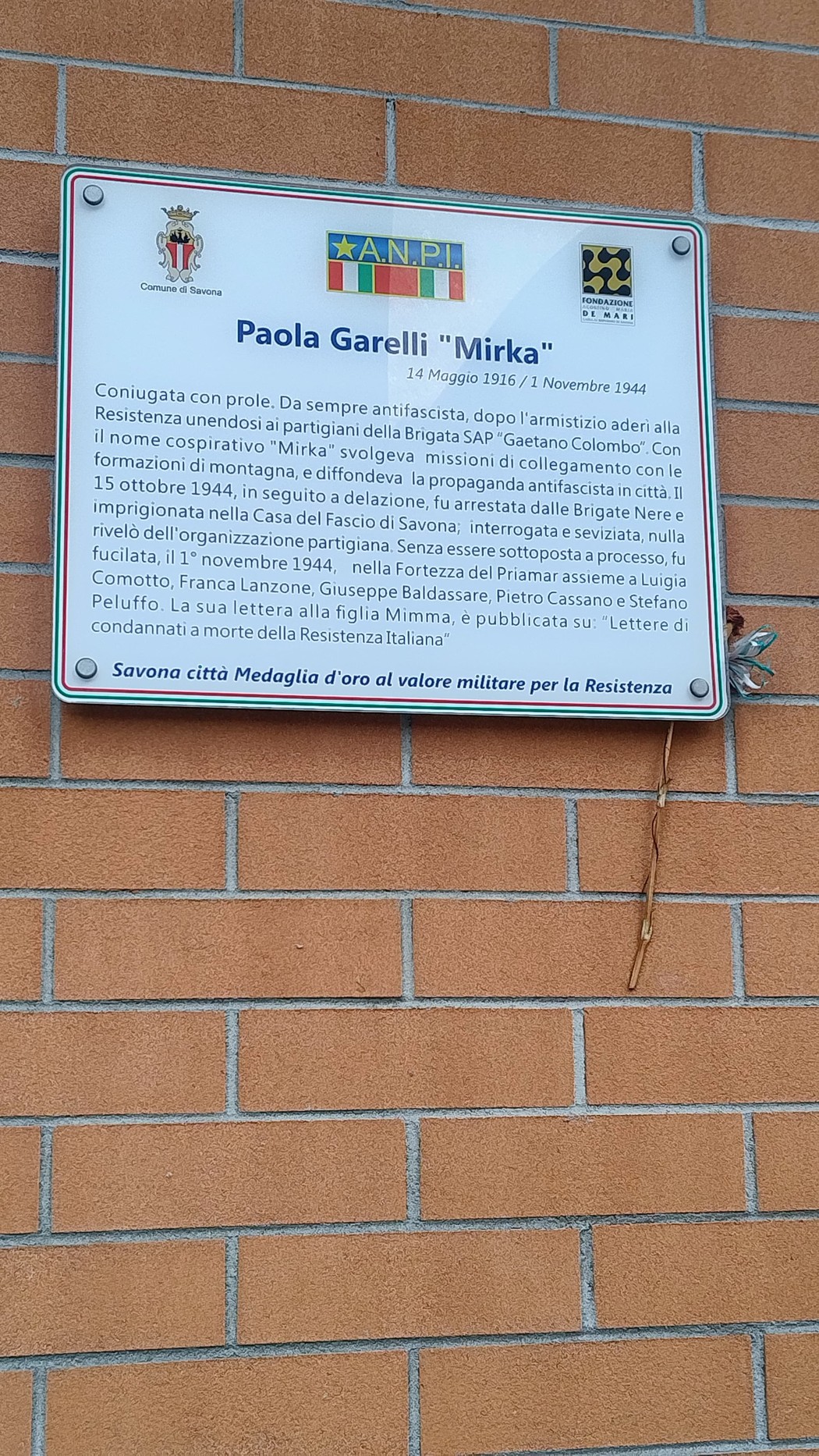 Targa commemorativa dedicata a Paola Garelli, attivista della Resistenza, con dettagli storici e riconoscimenti.