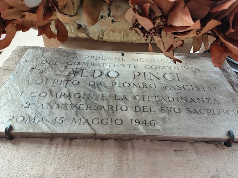 Lapide commemorativa dedicata ad Aldo Pinci, vittima del fascismo, con decorazioni floreali.