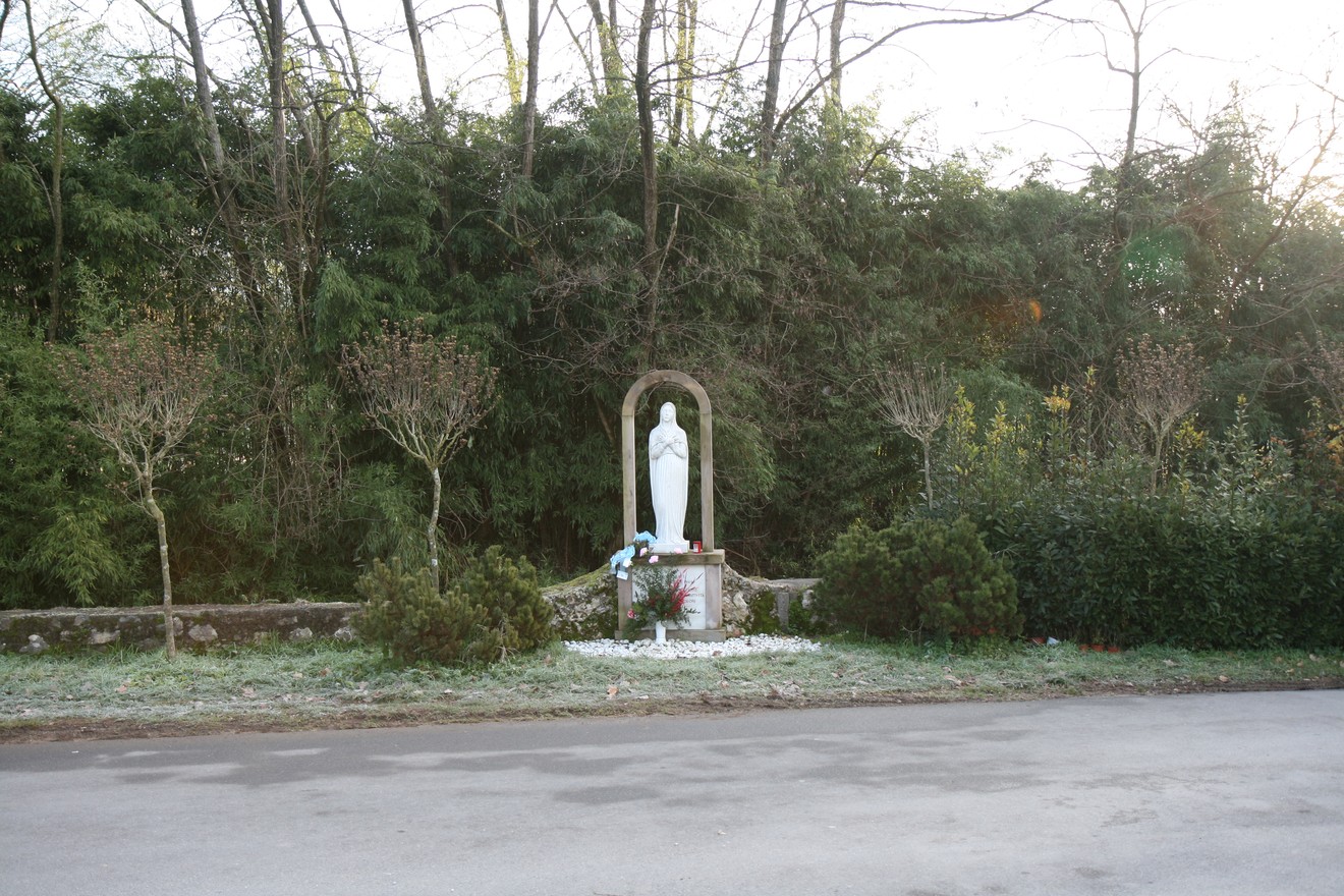 Monumento al cimitero di San Martino, immerso nel verde, con statua e aiuole curate.