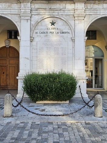 Lapide commemorativa con iscrizioni, dedicata ai Caduti per la Libertà, incastonata in un'architettura storica.