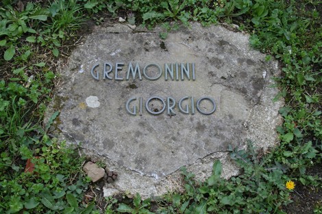 Monumento commemorativo nel cimitero di Stia, con dettagli in rilievo su una lapide di pietra.