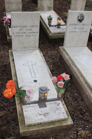 Tombe con fiori e lumini, dedicate ai caduti per la libertà, in un ambiente silenzioso e rispettoso.