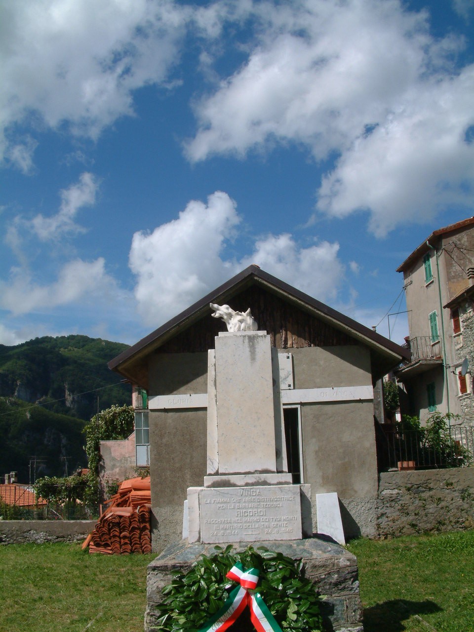 Monumento commemorativo dedicato alle vittime della strage di Vinca, immerso nella natura e nel cielo di Toscana.