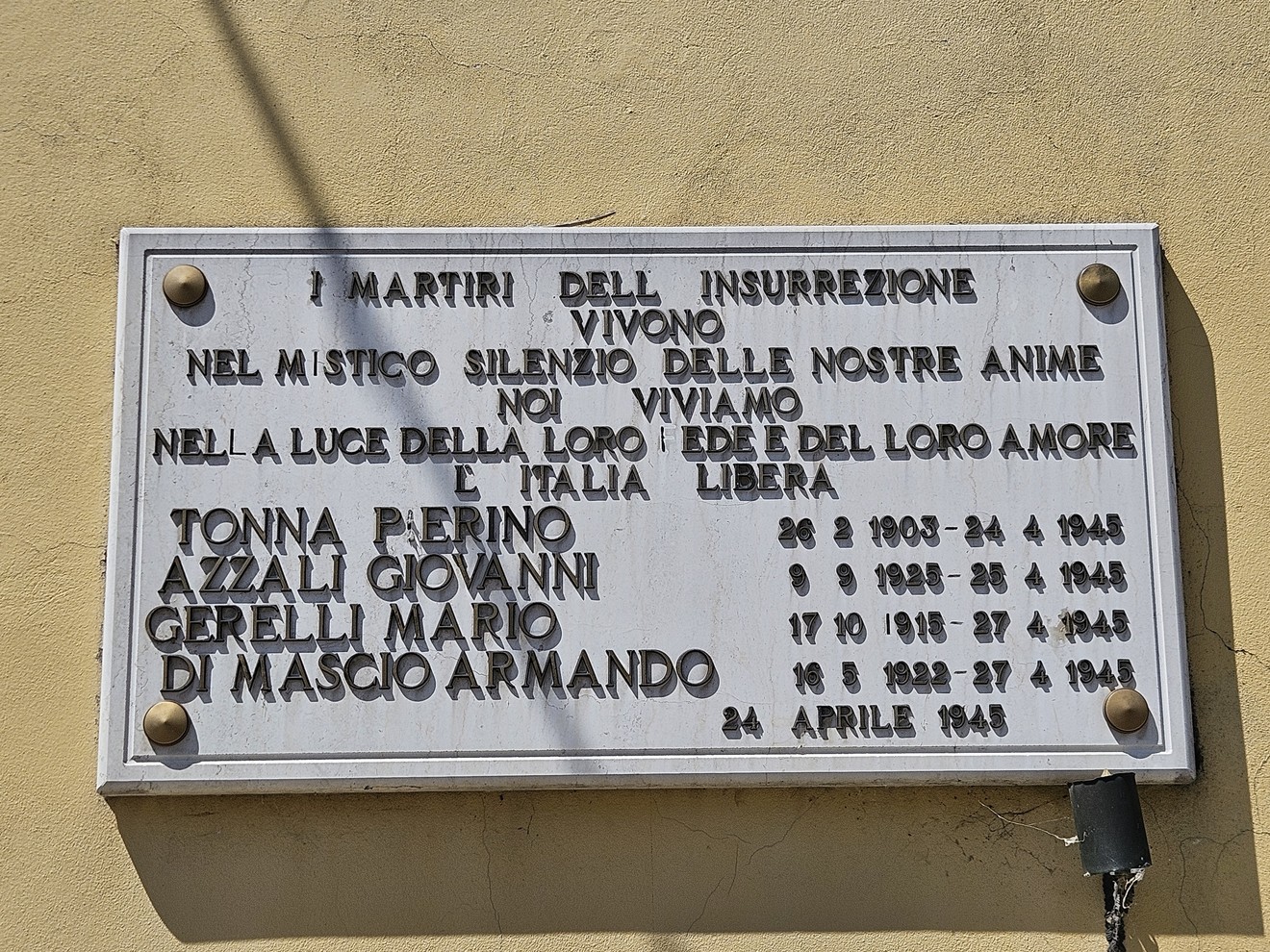 Lapide commemorativa dedicata ai martiri dell'insurrezione, con nomi e date incisi. Rappresenta un tributo alla memoria storica.