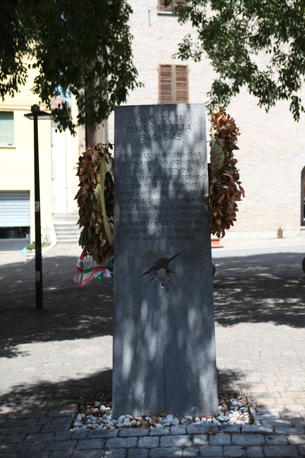 Monumento ai Caduti per la libertà, con decorazioni floreali e un'ambientazione urbana tranquilla.