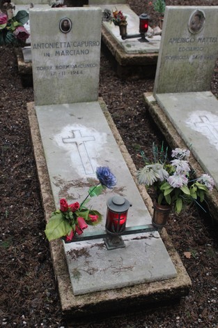 Tombe perpetue decorate con fiori e candele in un cimitero, dedicate ai caduti per la Libertà.