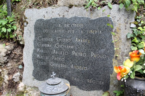 Lapide commemorativa dedicata ai caduti per la Libertà a Vertova, con fiori e candele.