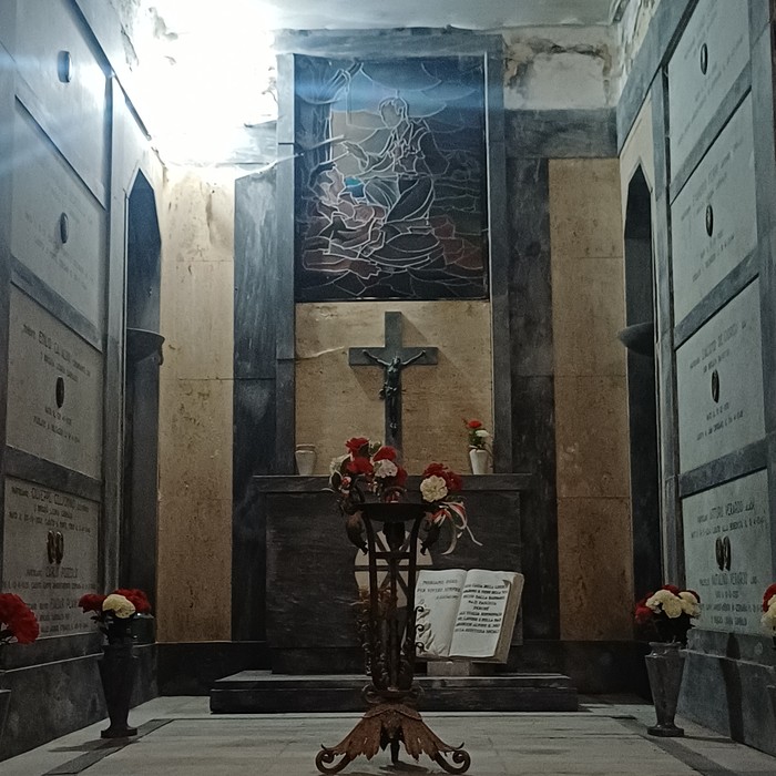 Sacrario con vetrata istoriata, crocifisso e libro aperto su leggio, lapidi con iscrizioni alle pareti laterali.