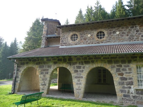 Vista del Tempio ai Dodici Martiri, un edificio in pietra circondato da alberi e con archi caratteristici.