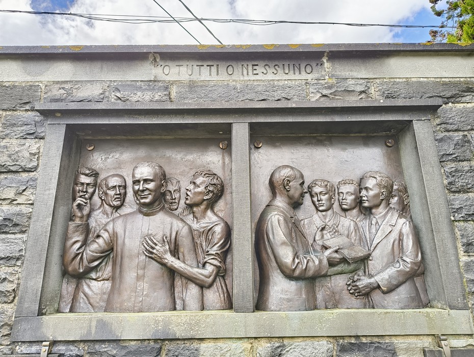 Monumento a Comini, rilievo commemorativo che celebra l'impegno sociale e culturale nella comunità.