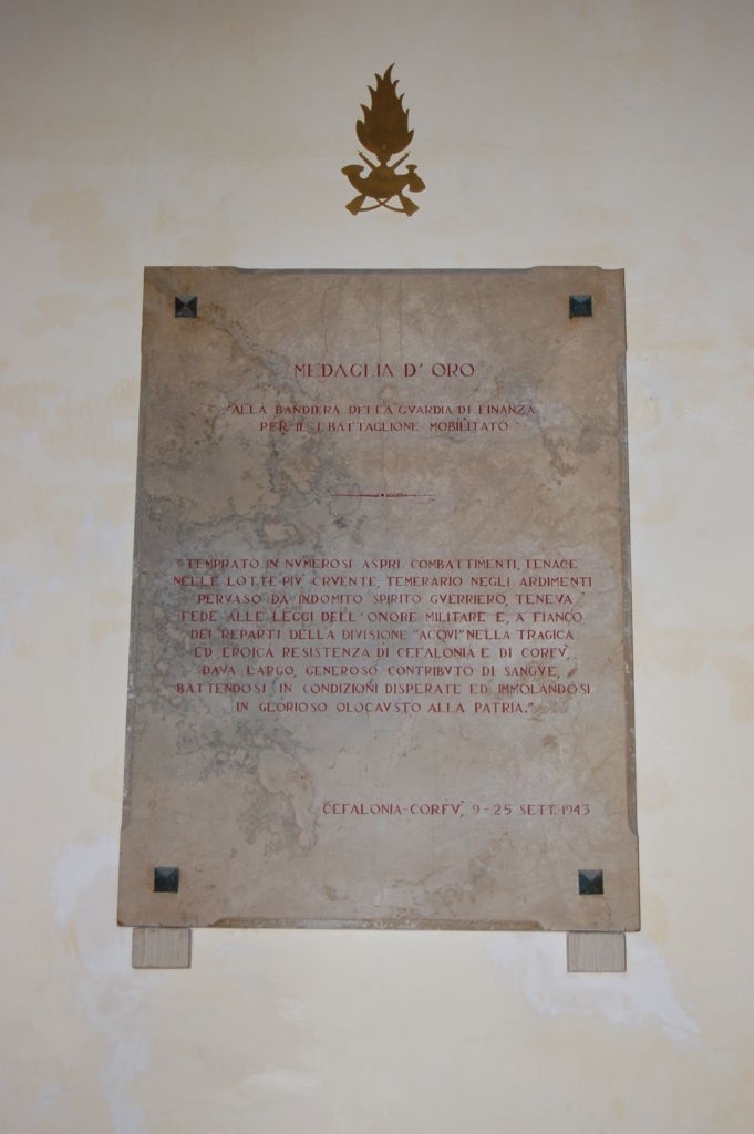 Lapide commemorativa del I Battaglione mobilitato, con simboli militari e dedica ai caduti.