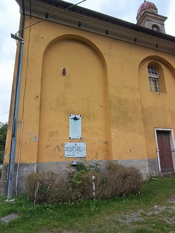 Lapide commemorativa ai Caduti per la Libertà, situata sulla parete di una chiesa gialla.