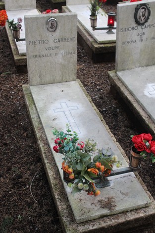 Tombe con lapidi dedicate ai caduti per la Libertà, decorate con fiori e candele.